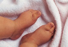 Close-up of a baby's feet against a pink blanket.