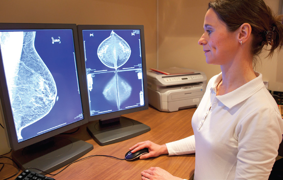Woman reviewing mammography images on computer screens.